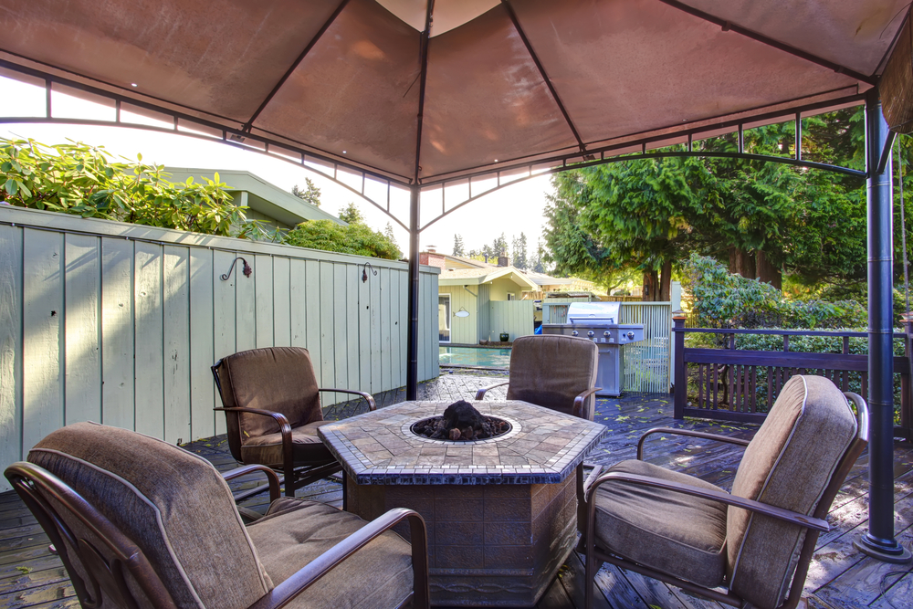 style your patio with wooden deck with railings and gazebo with fire pit and chairs