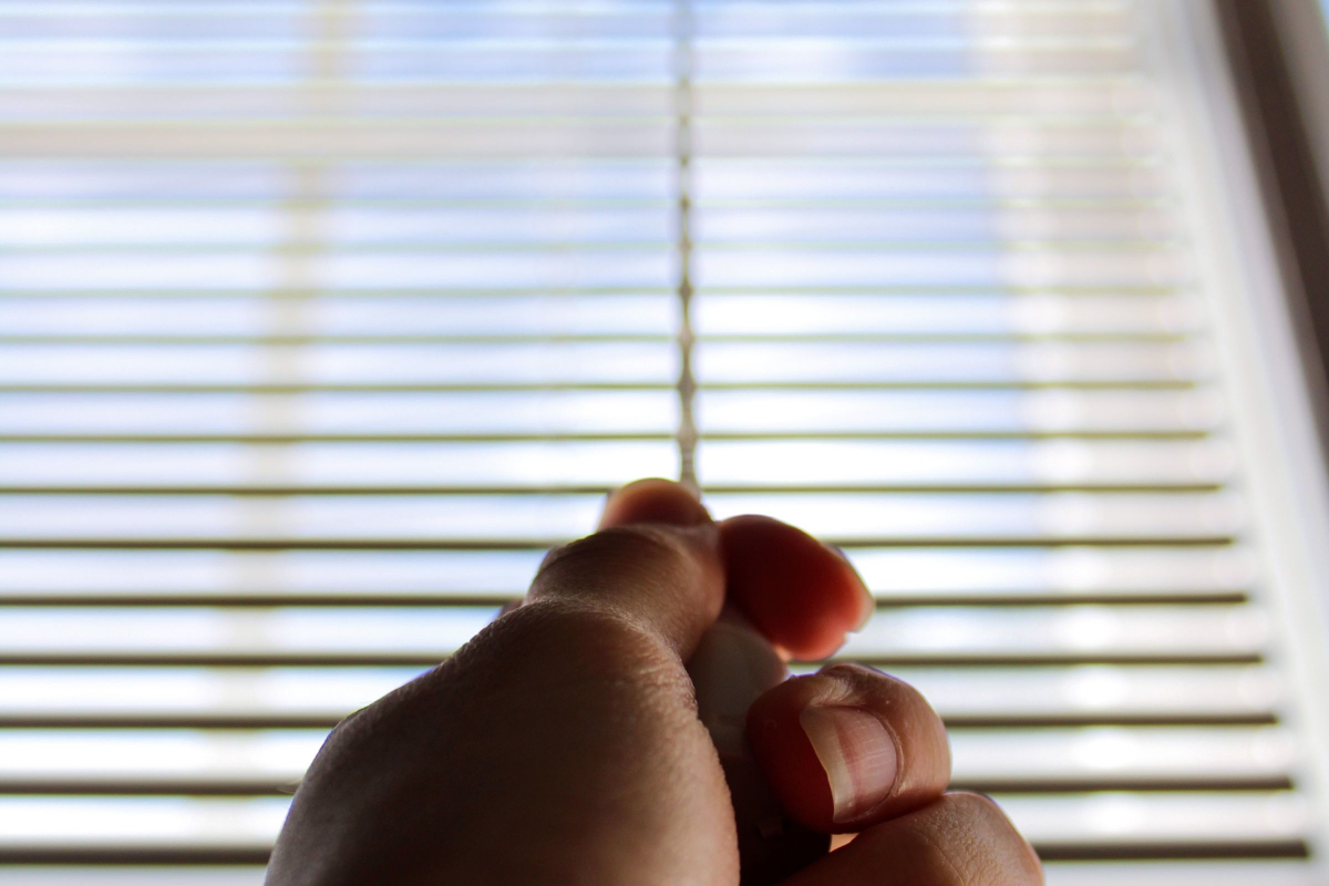 A man hand holding the window blinds
